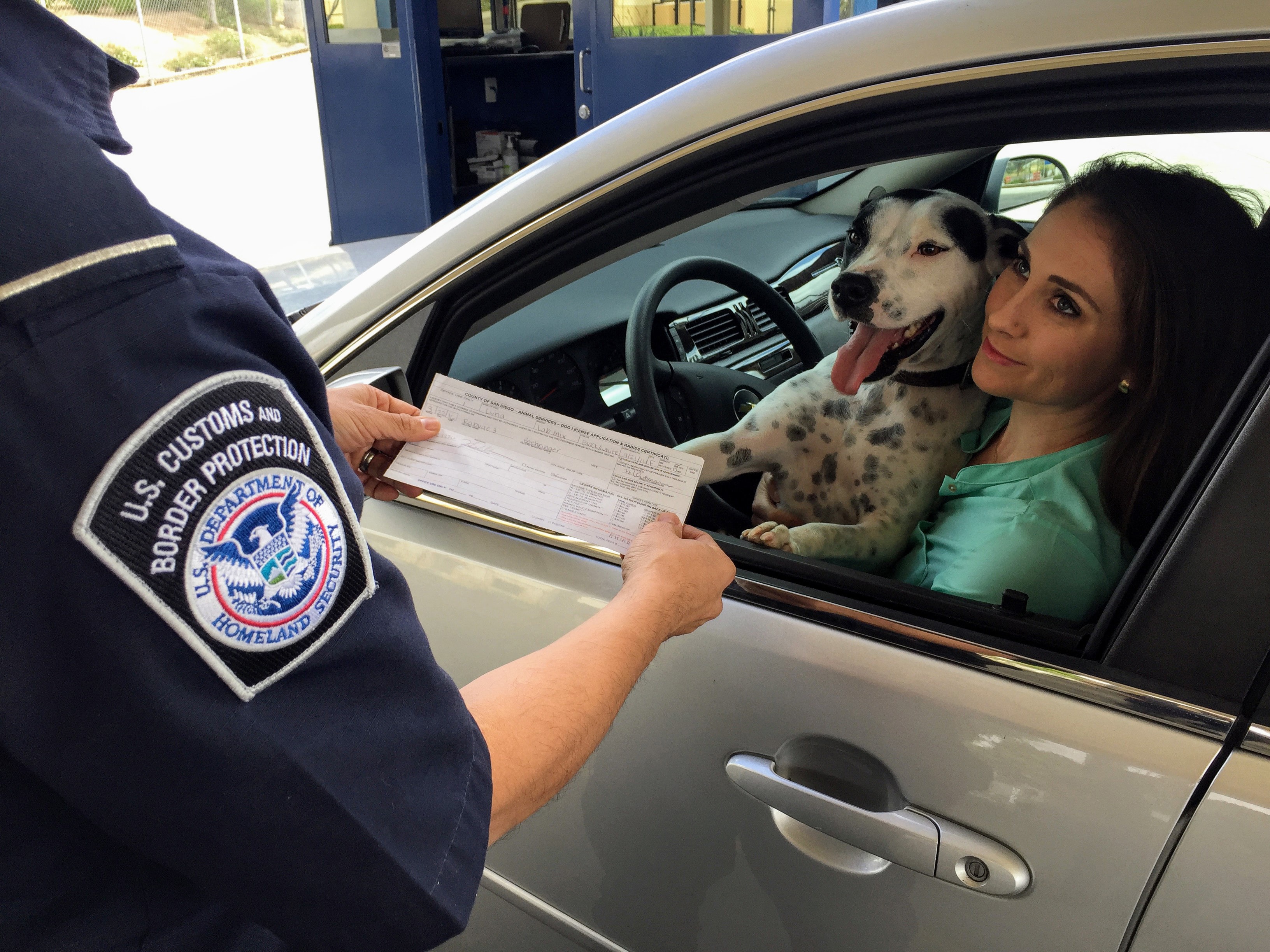 Border crossing, agent interviews woman with dog in car